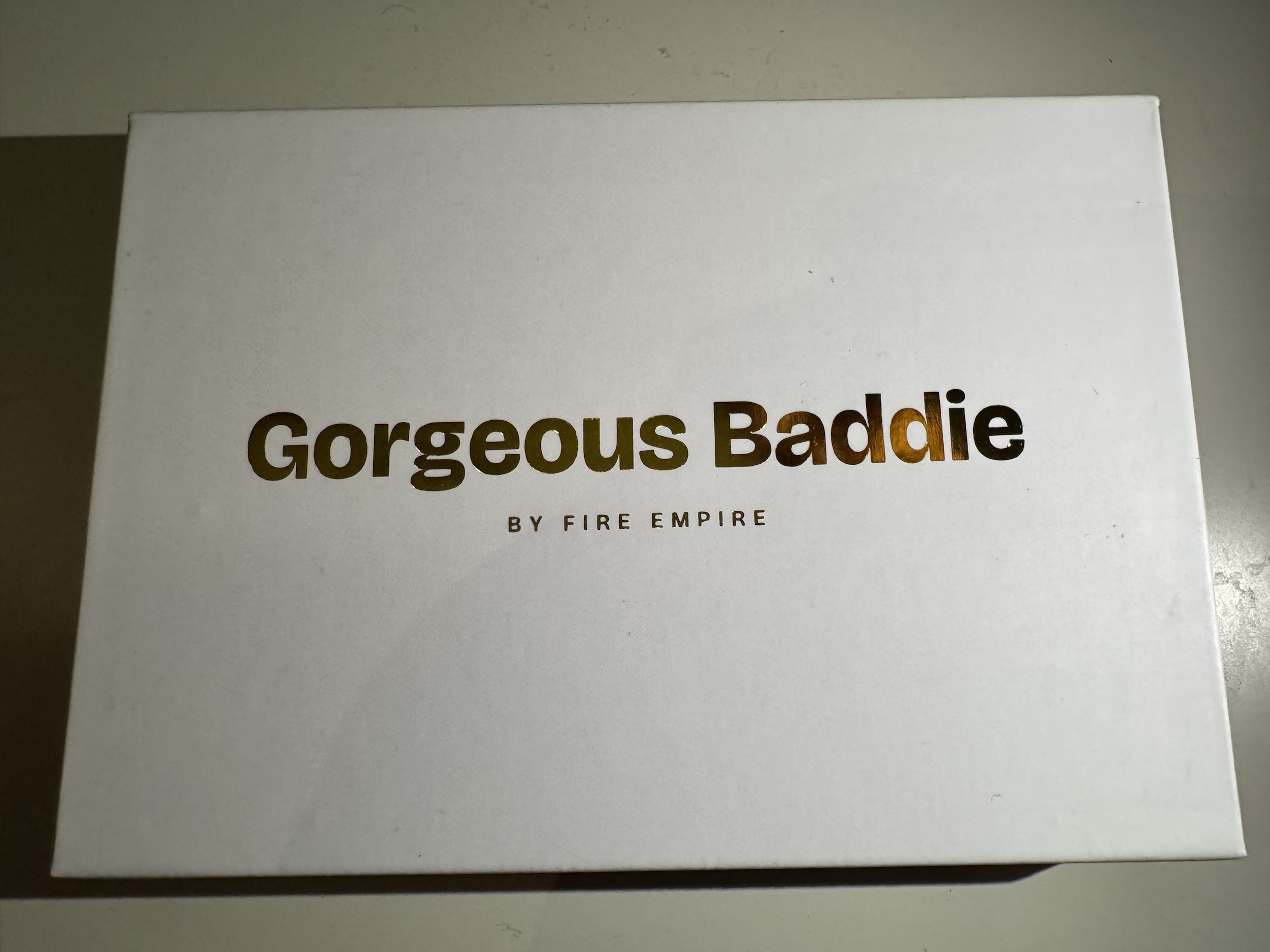 Gorgeous Baddie by Fire Empire gift box, gold-foil wordmark on a white rigid box