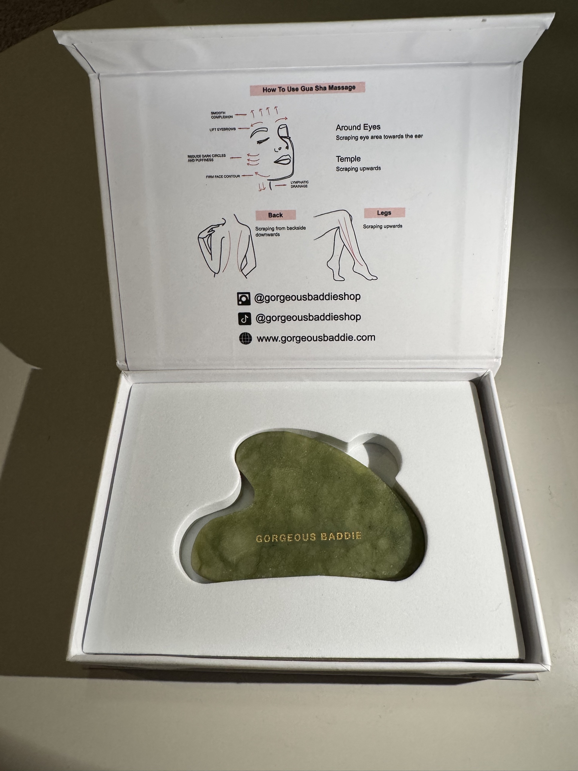 Gorgeous Baddie jade gua sha sample, laser-engraved in gold, resting in its gift box